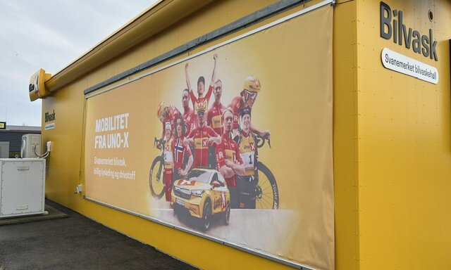 Stort PVC-banner montert på gul fasade